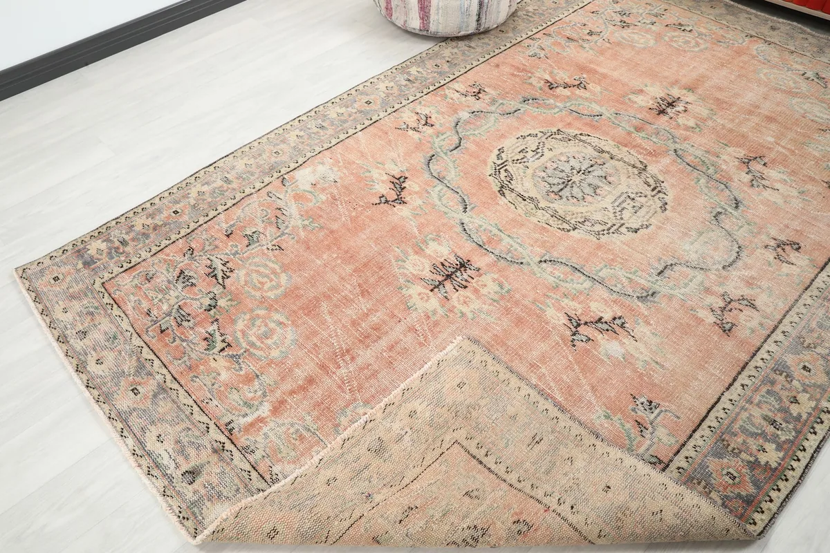 Corner of the rose vintage rug folded back, revealing the cotton foundation and hand-knotted construction