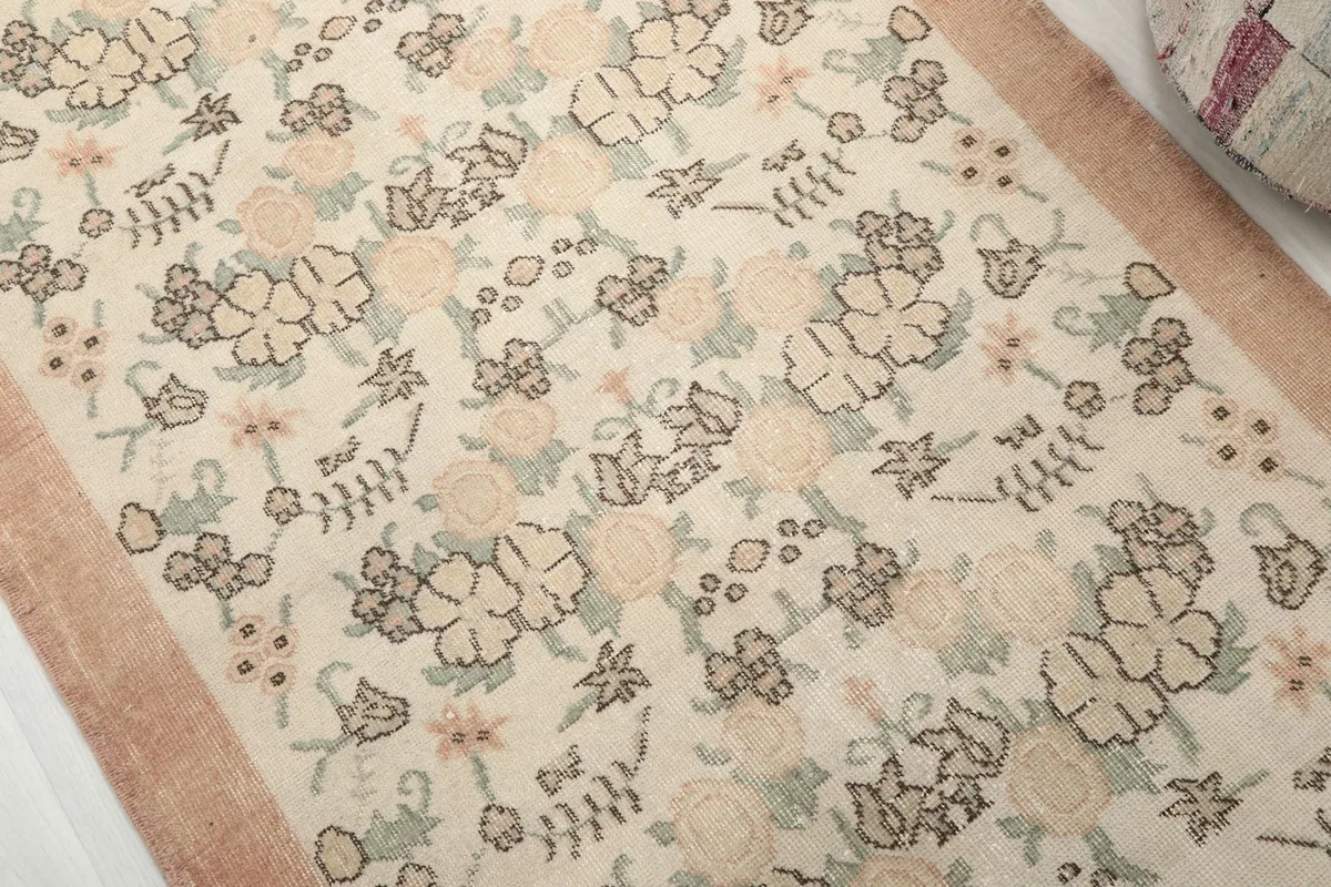 Detailed view of the ivory field with rose, green, and brown floral motifs