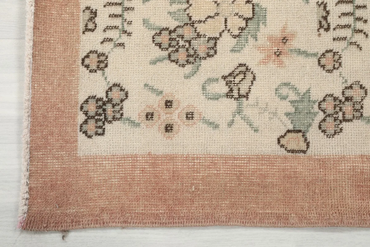 Detail of the rose colored border and corner of the rug, showing slight wear
