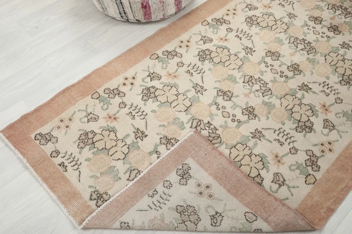 Corner of the rug folded back, revealing the reverse side and hand-knotted structure
