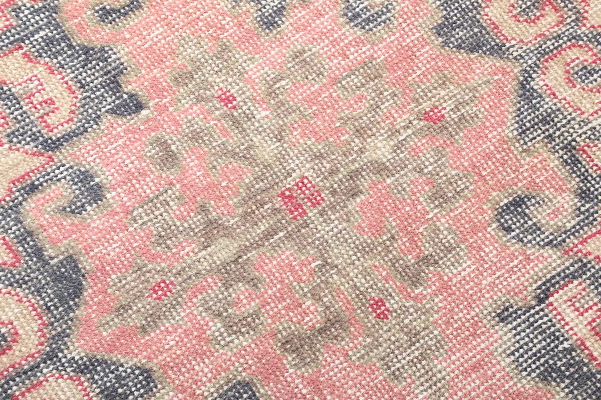 Close-up of the low wool pile, showing the faded rose and navy colors and texture