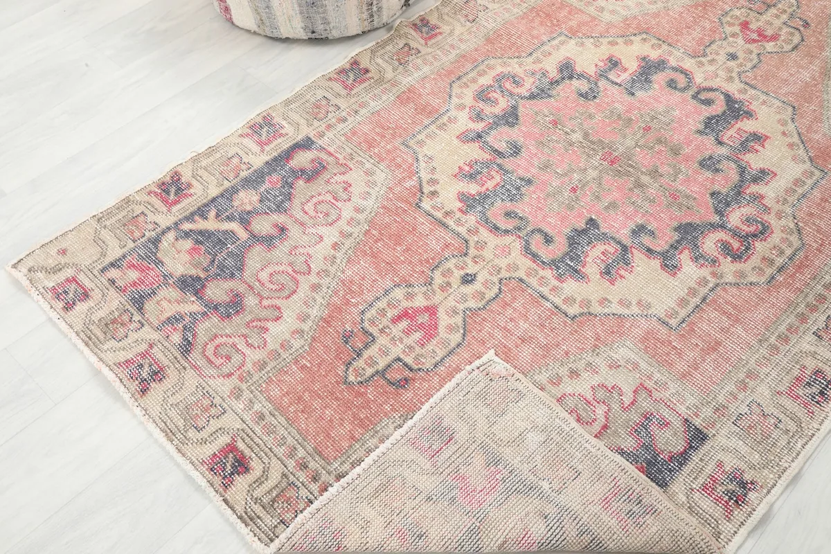 Corner of the vintage rug folded to show the hand-knotted wool pile and cotton foundation