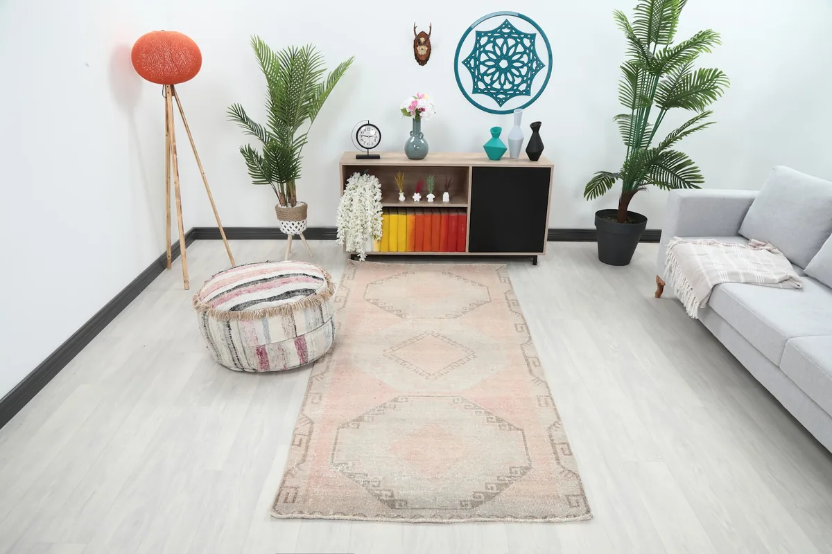 Vintage Anatolian runner rug with rose and beige tones in a contemporary living room setting.