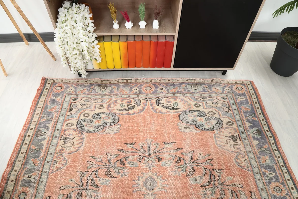 Partial overhead view of the orange vintage rug, showing one end and a furniture piece