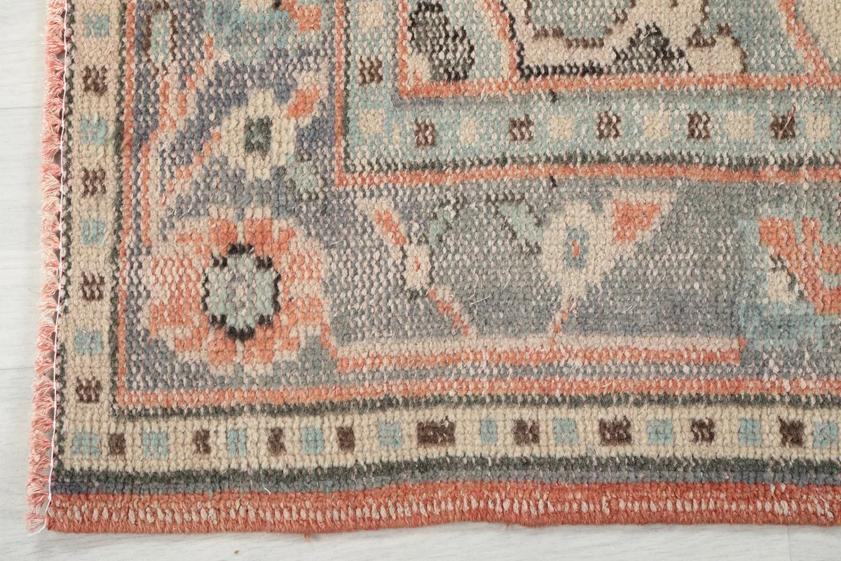 Detail of the border design and faded colors of the orange and blue vintage rug