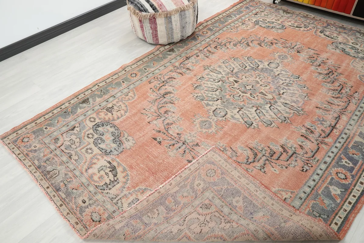 Angle view of the vintage rug with a corner folded back, showing the back of the rug