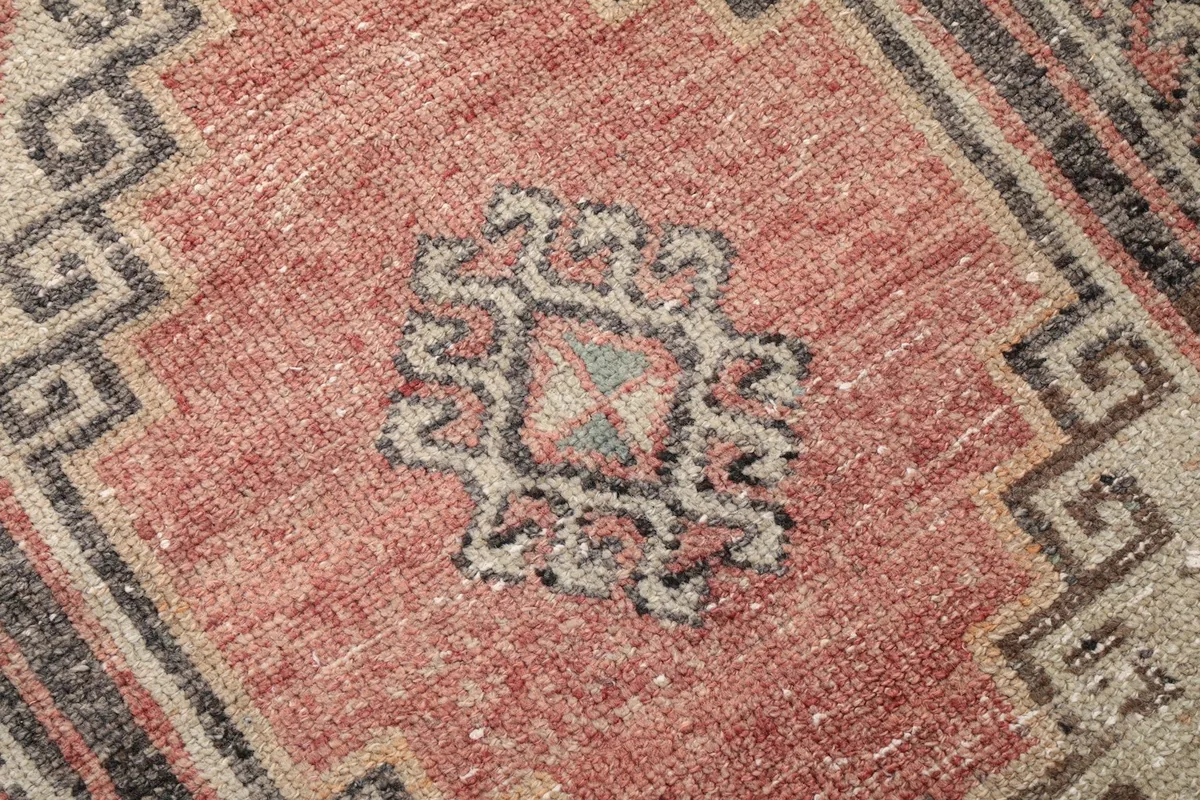 Close-up of the intricate wool pile and faded rose and gray colors within a medallion