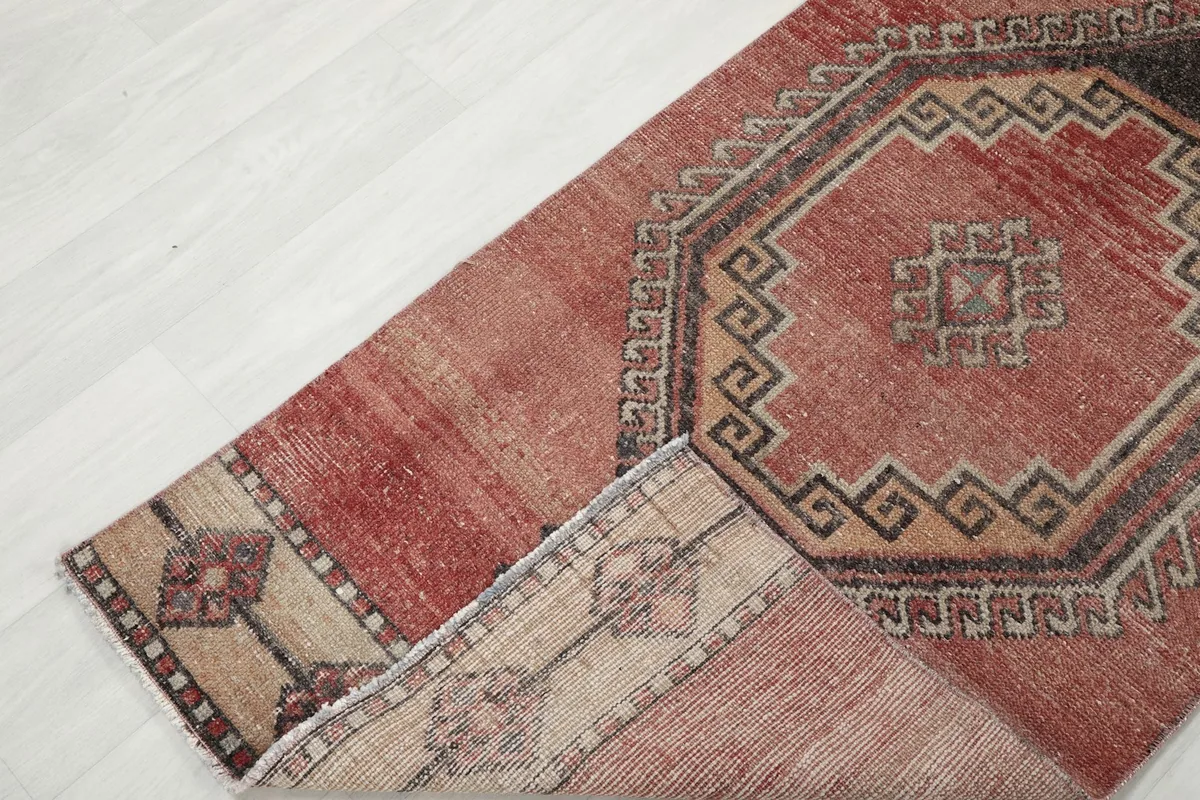 A corner of the runner rug folded back, revealing the cotton foundation