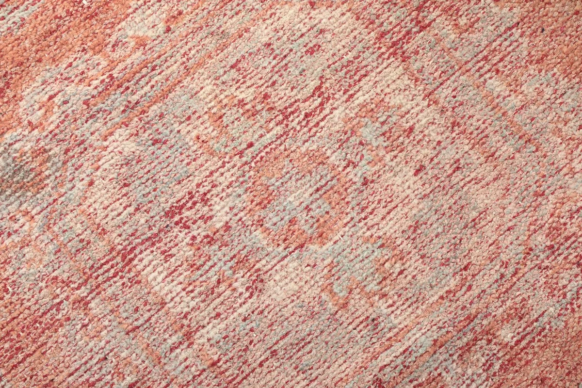 Detailed close-up of the hand-knotted wool pile, showing the intricate faded rust and beige patterns