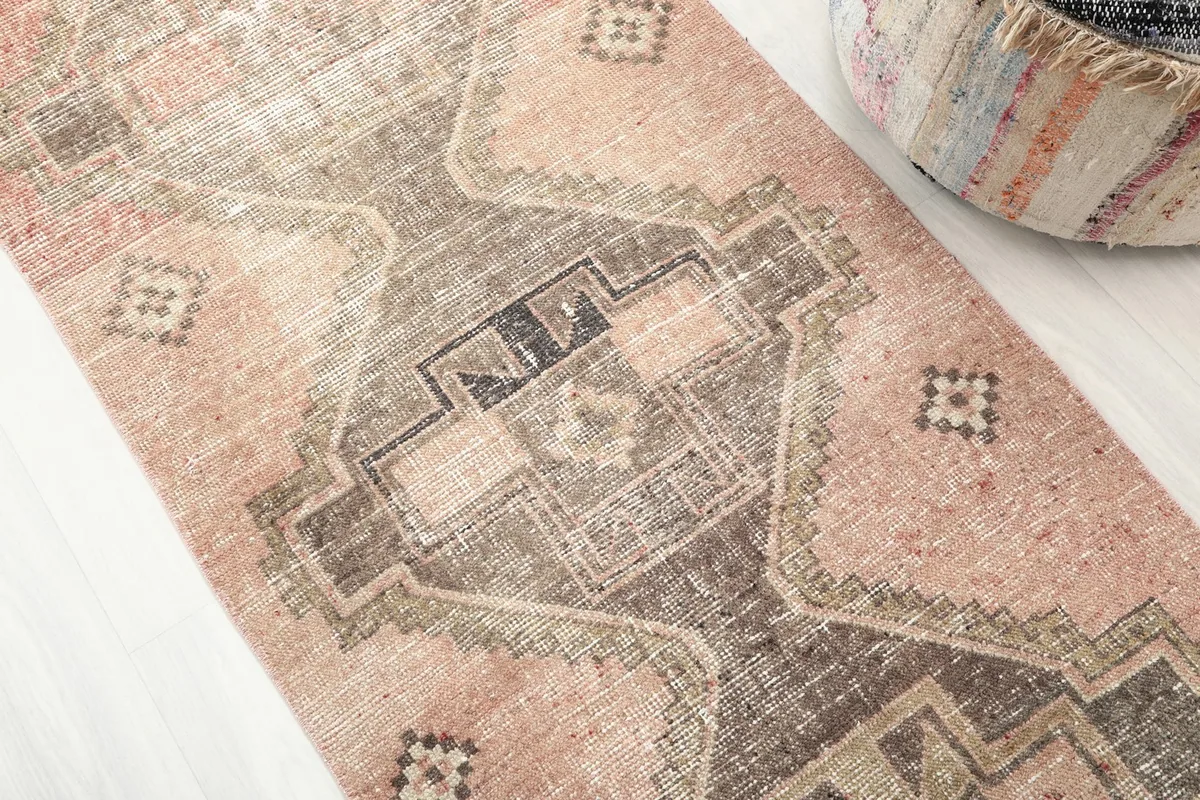 Close-up of the tribal geometric motifs in gray, charcoal, and brown against the rose background.
