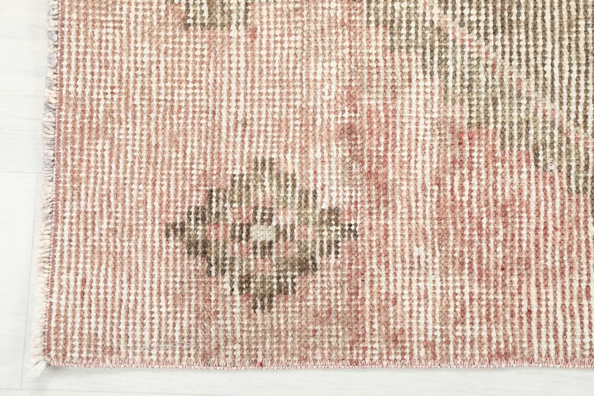 Texture close-up of the low wool pile and the subtle color blending of the rose and beige threads.