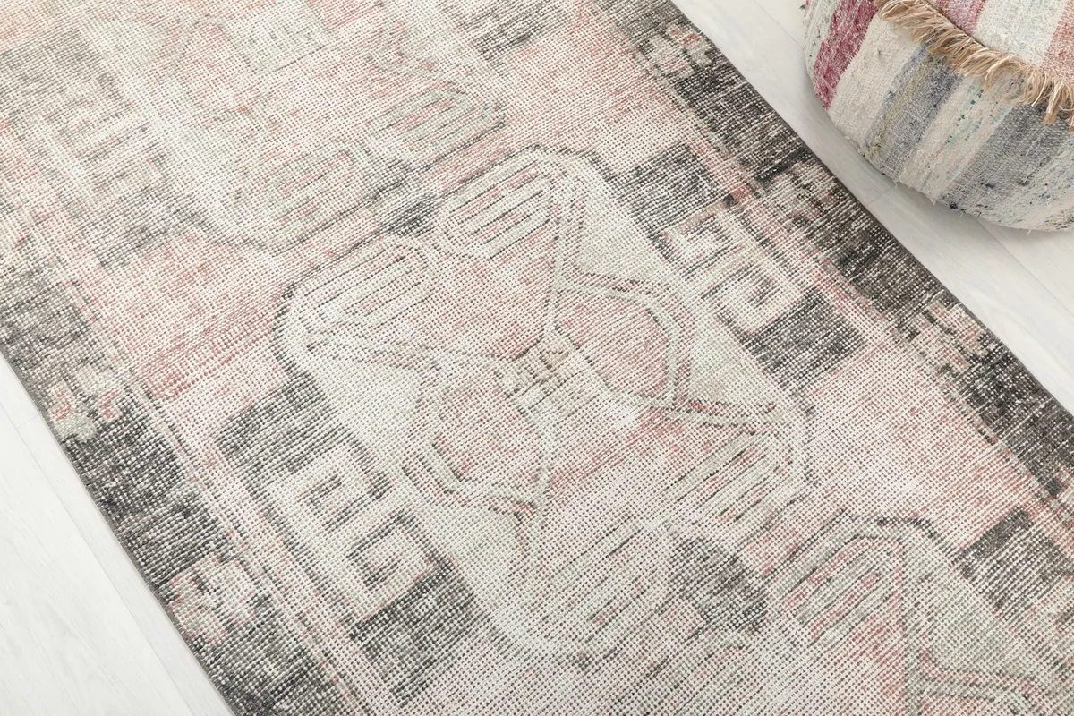 Close-up detail of the faded rose and charcoal geometric patterns on the runner rug.
