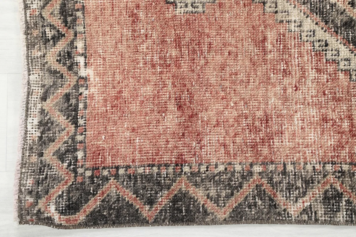 Close-up of the runner's border, featuring a zigzag pattern in charcoal and beige tones