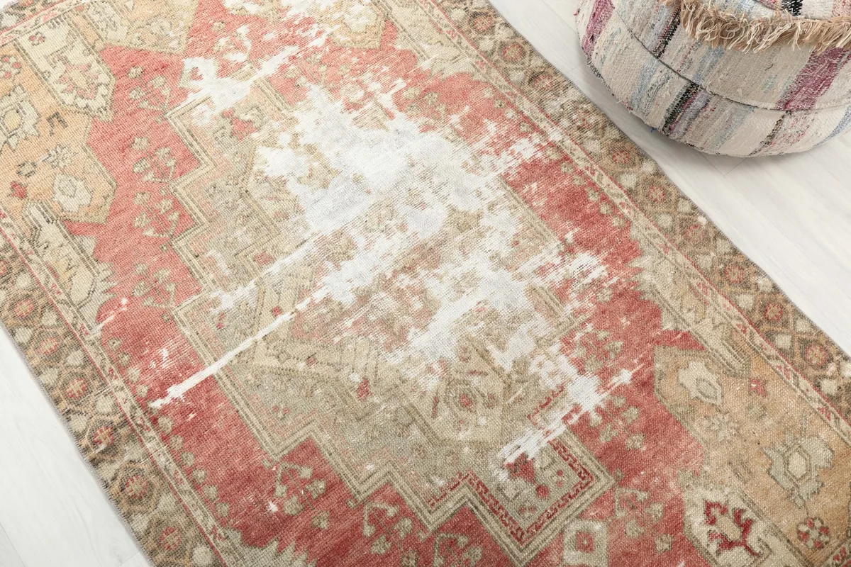 Detailed view of the rug's surface, highlighting the faded rose and beige colors and geometric motifs