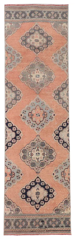 Top view of a rust colored vintage Anatolian runner rug with geometric medallions on a white background.