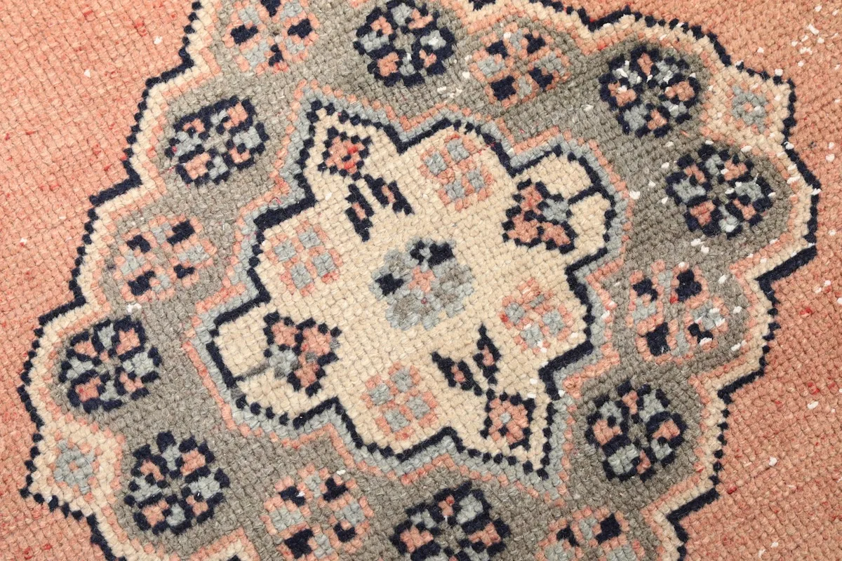 Close-up of a single gray and cream geometric medallion, highlighting the hand-knotted wool pile.