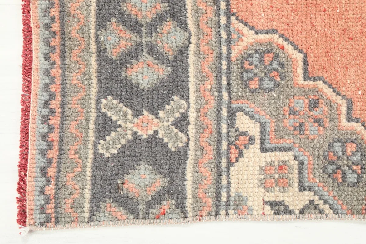 Close-up of the rug's border design, featuring geometric motifs in navy, gray, and rust colors.