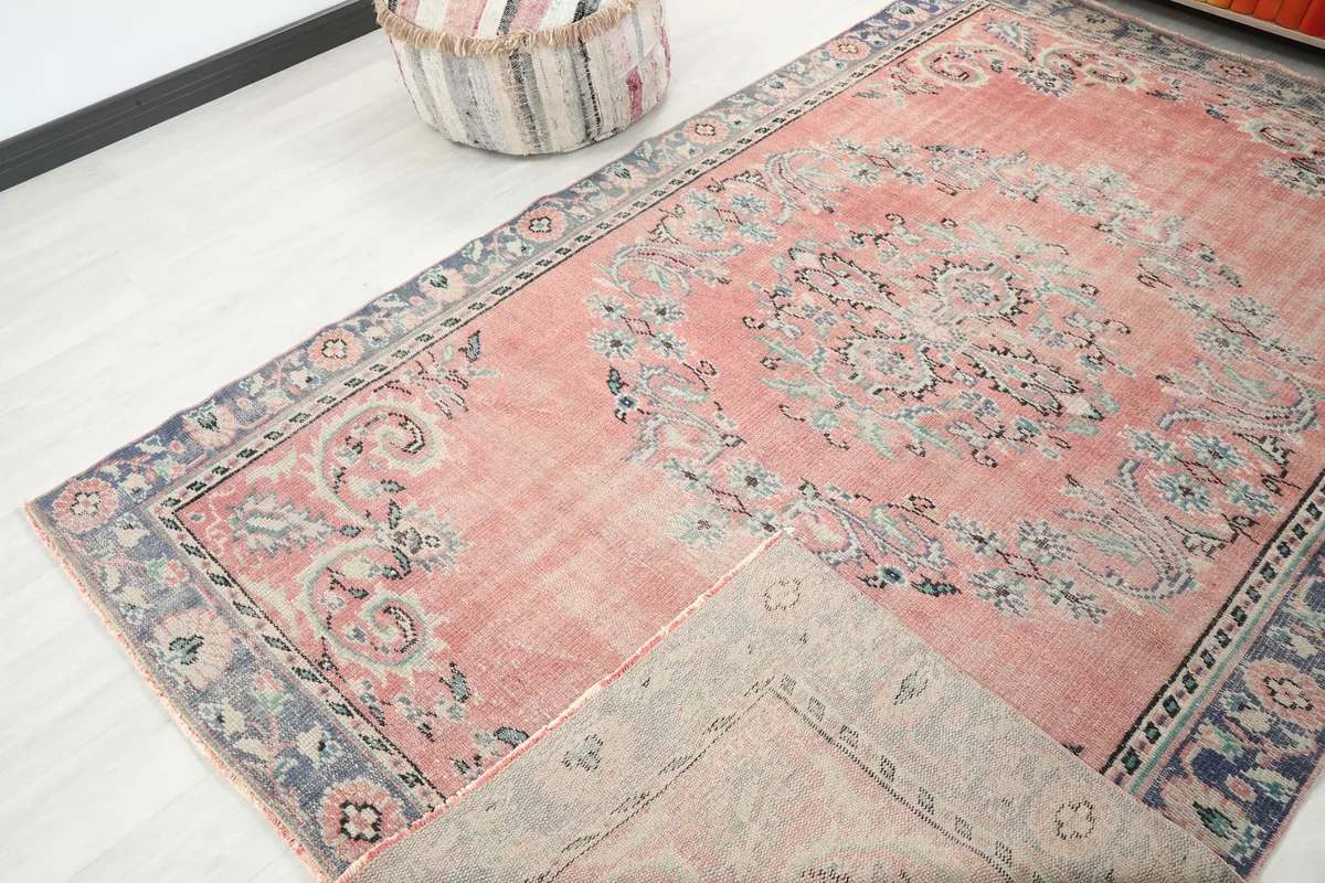 Partial view of the rug, with a corner folded back to reveal the back of the hand-knotted wool pile.