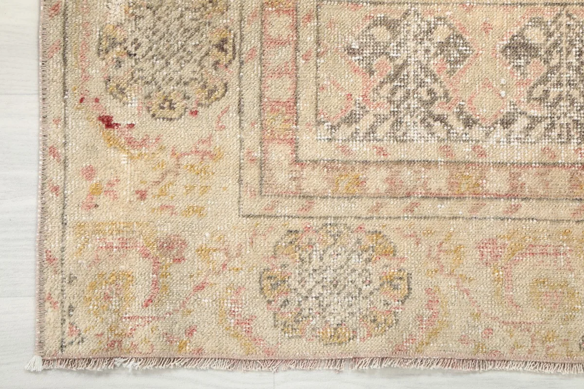 Close-up of the beige border with subtle pink, gray, and gold geometric details.