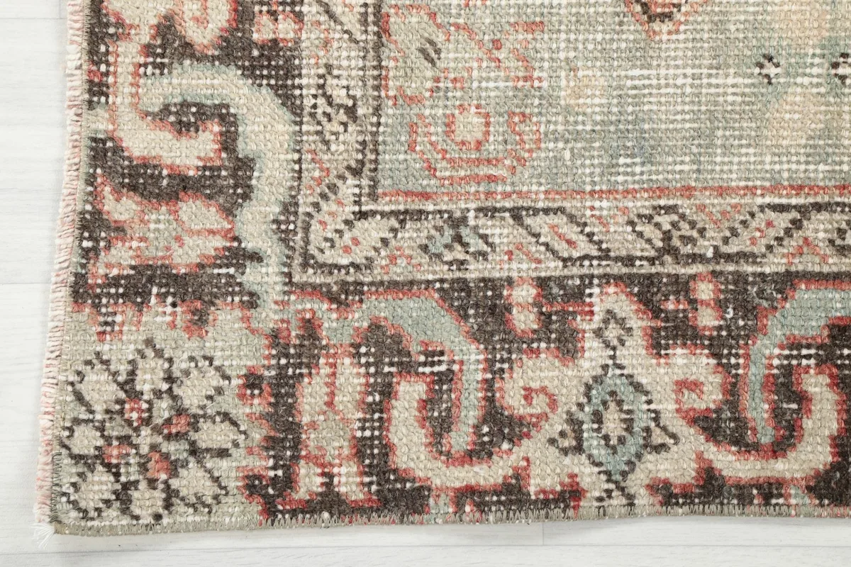 Corner detail of the rug, illustrating the border design and signs of vintage patina