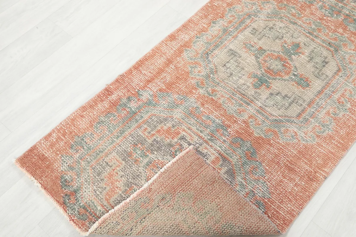 View of the rust runner rug folded over, showing the front and back textures