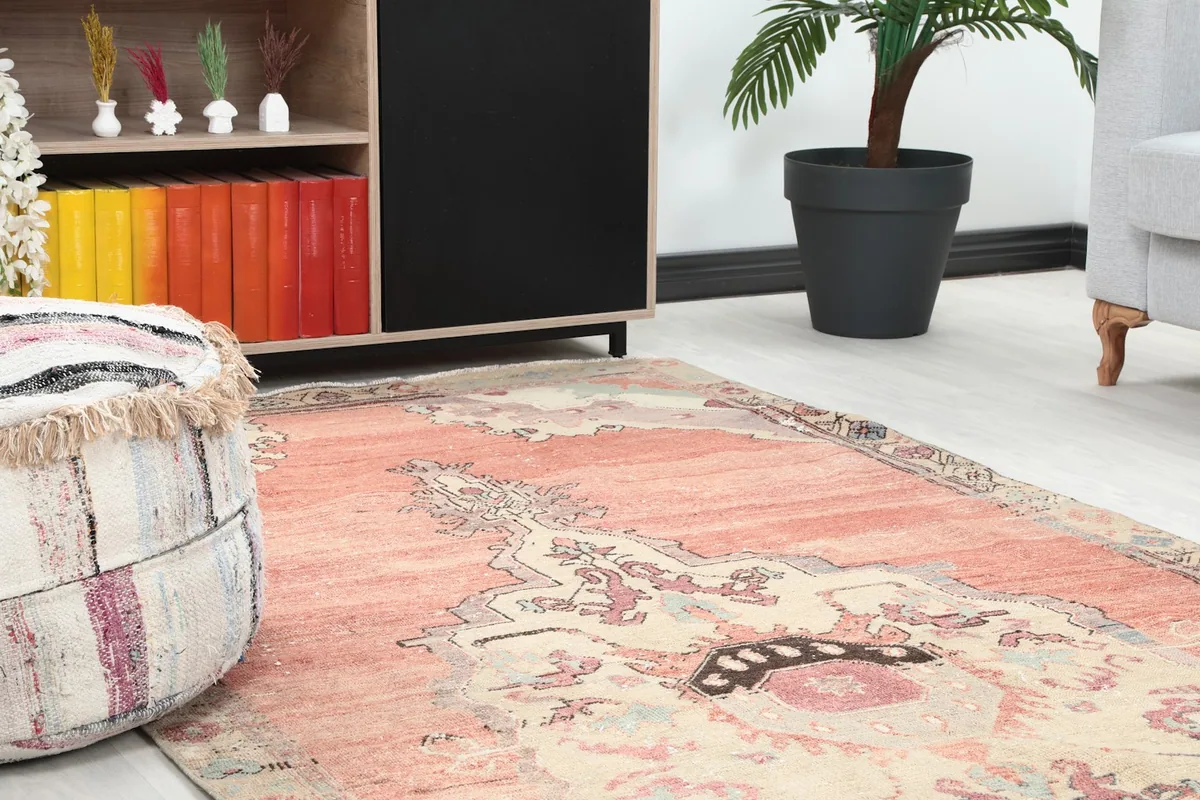 Close-up view of the rose and beige rug in a room setting, showing texture near a decorative pouf.