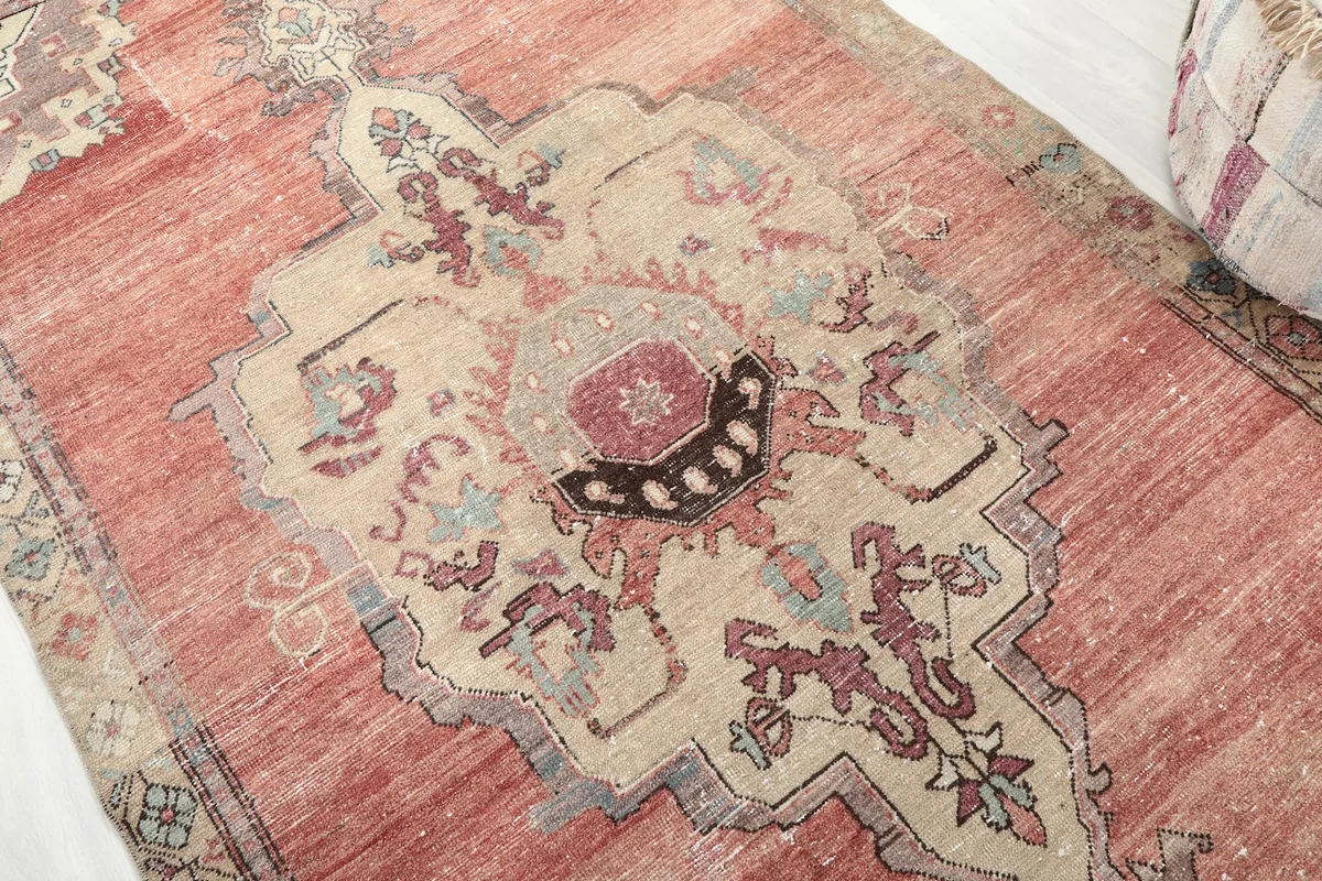 Detailed view of the central beige medallion with rose, gray, and blue accents on the rug.