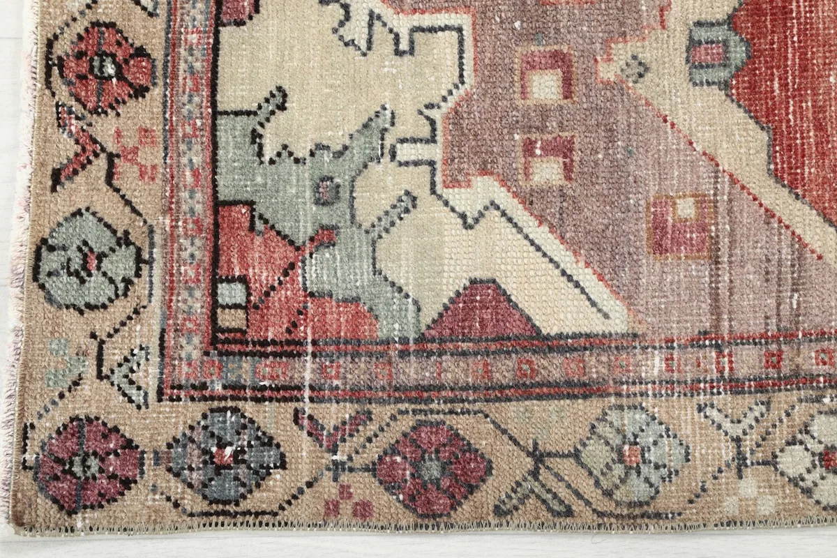 Detailed view of a corner of the rug, showing the geometric border pattern and fringe.