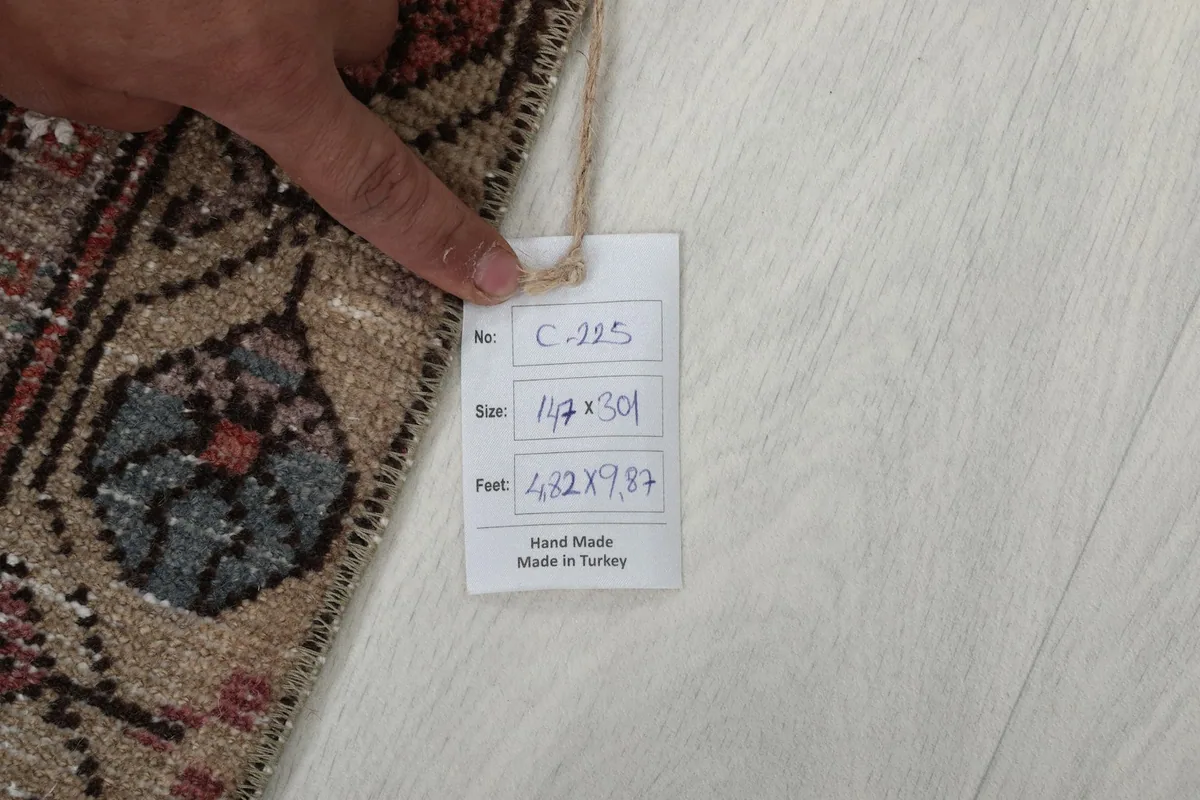 Hand pointing to a tag displaying the rug's dimensions and origin as hand-made in Turkey.