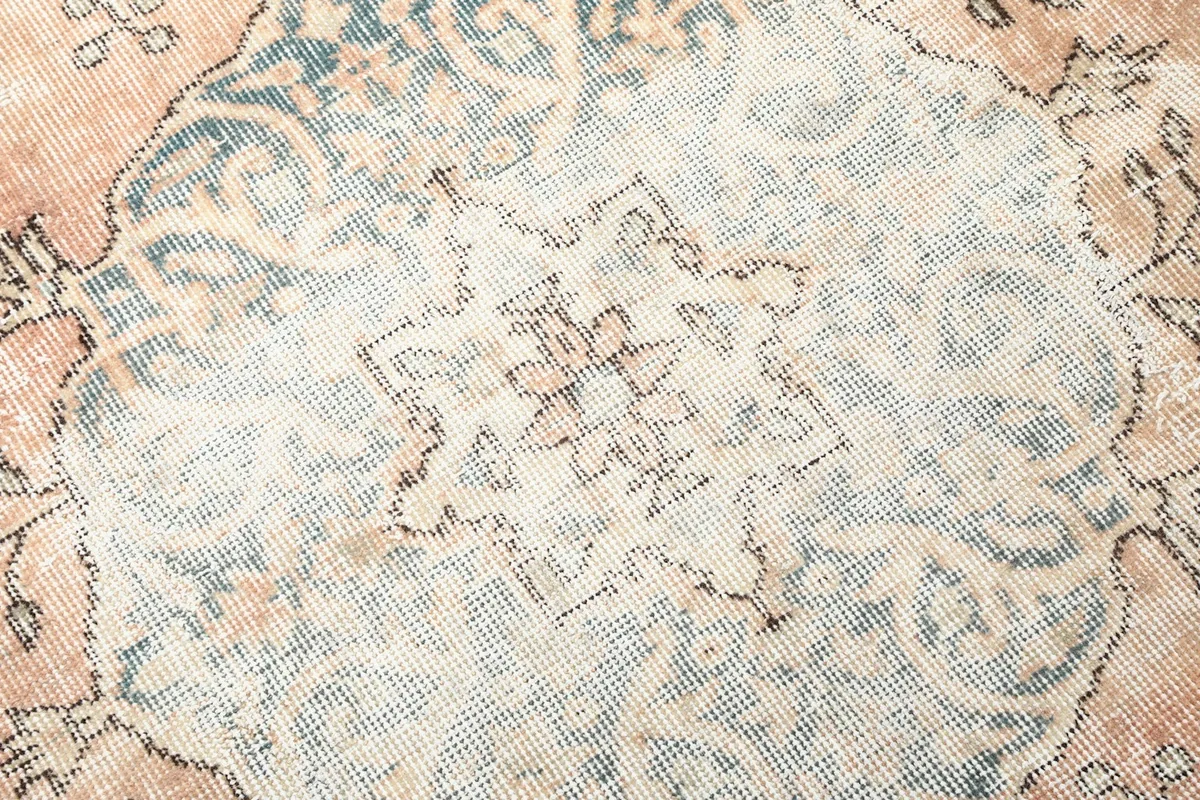 Close-up of the intricate design within the rug's central medallion, showing texture and colors.