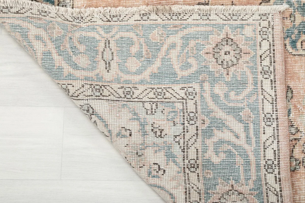 Underside view of the rug's corner, showing the hand-knotted construction and cotton foundation.