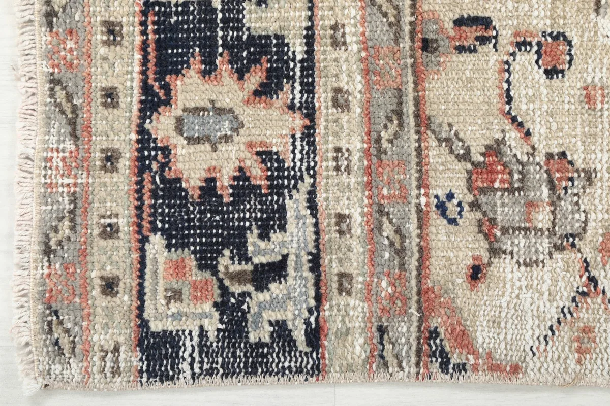 Close-up of the navy and beige border design with subtle rust accents and the fringe