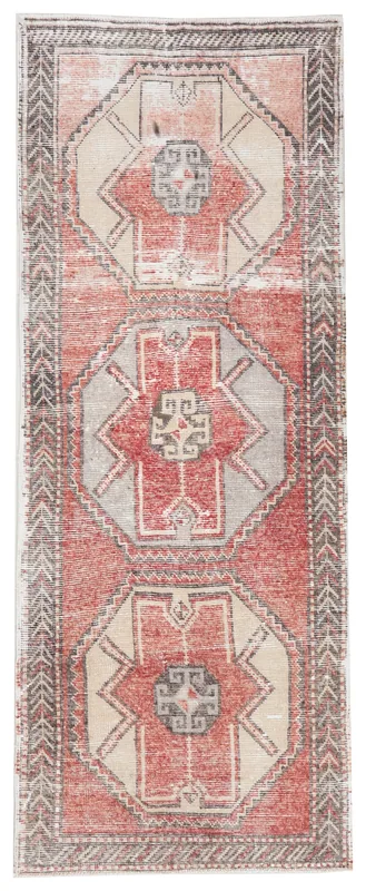 Full overhead view of a vintage red, beige, and gray geometric runner rug