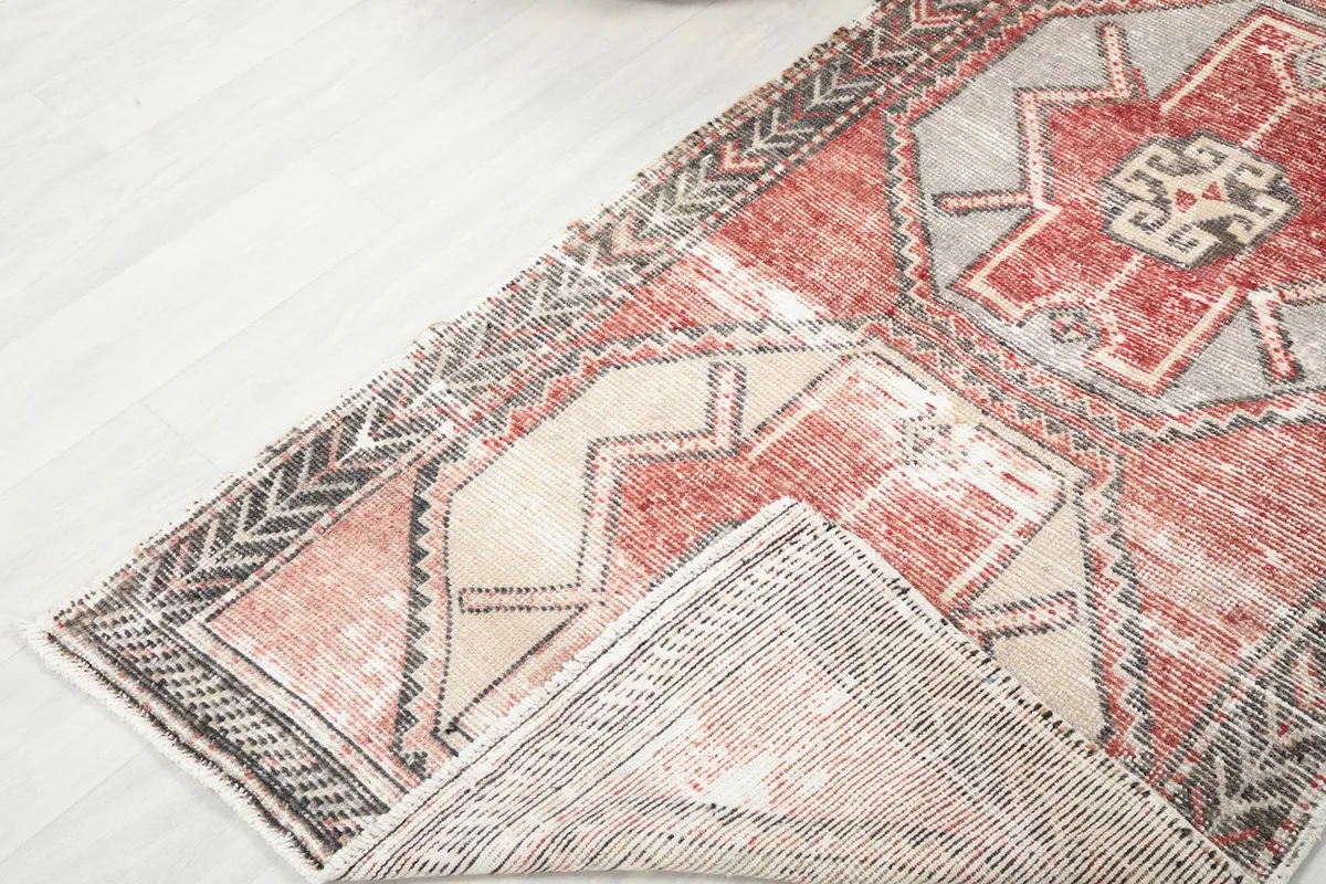 Corner of the rug folded back, showing the back of the rug and foundation