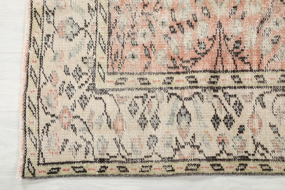 Corner detail of the beige border with geometric and floral charcoal designs