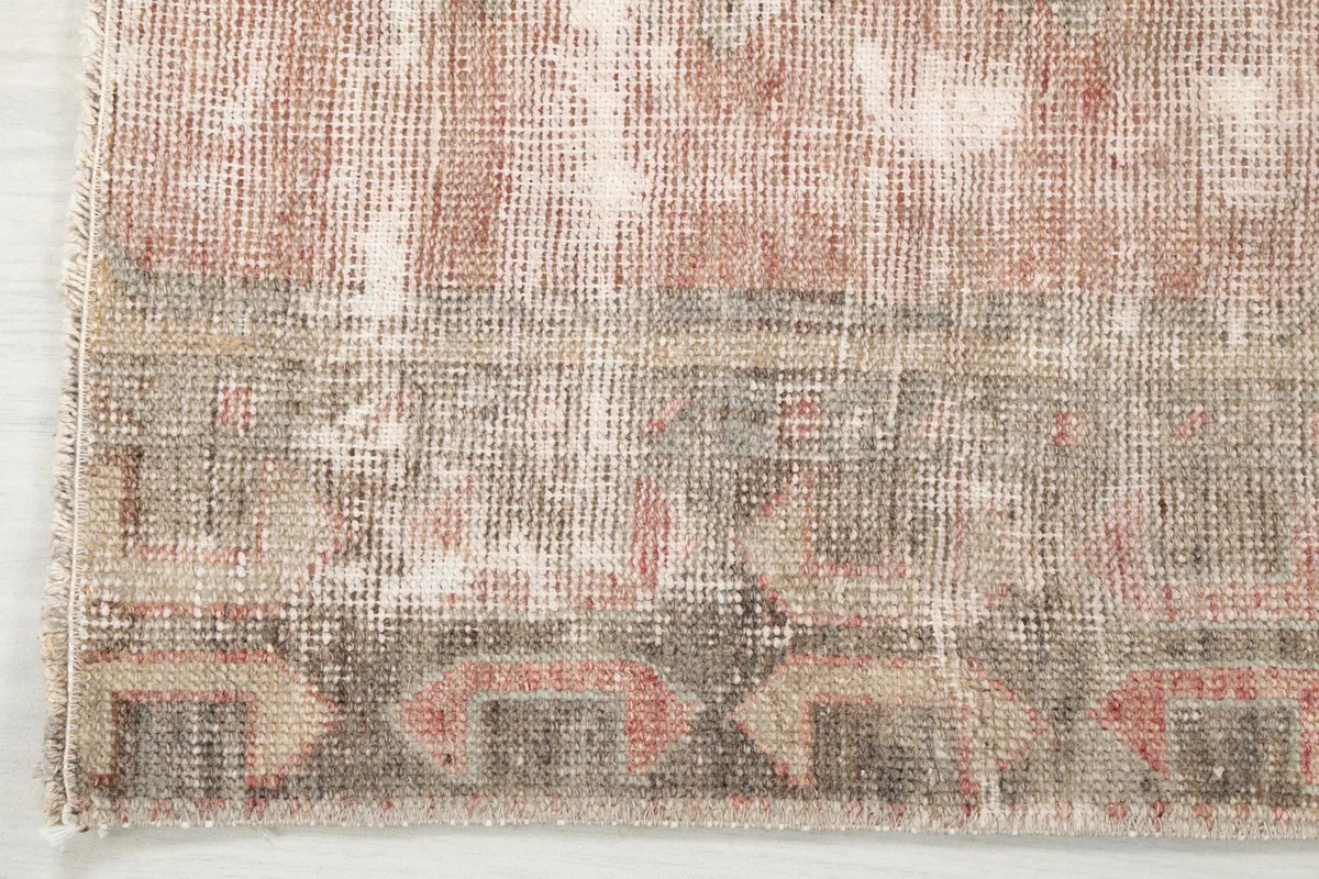 Close-up of the runner's border design and corner, revealing the aged wool fibers.