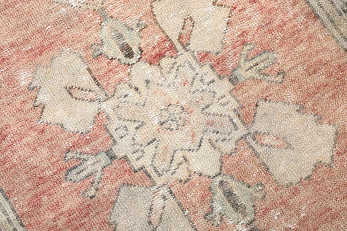 Detailed view of the low pile, showing the hand-knotted texture and faded rose and beige threads.