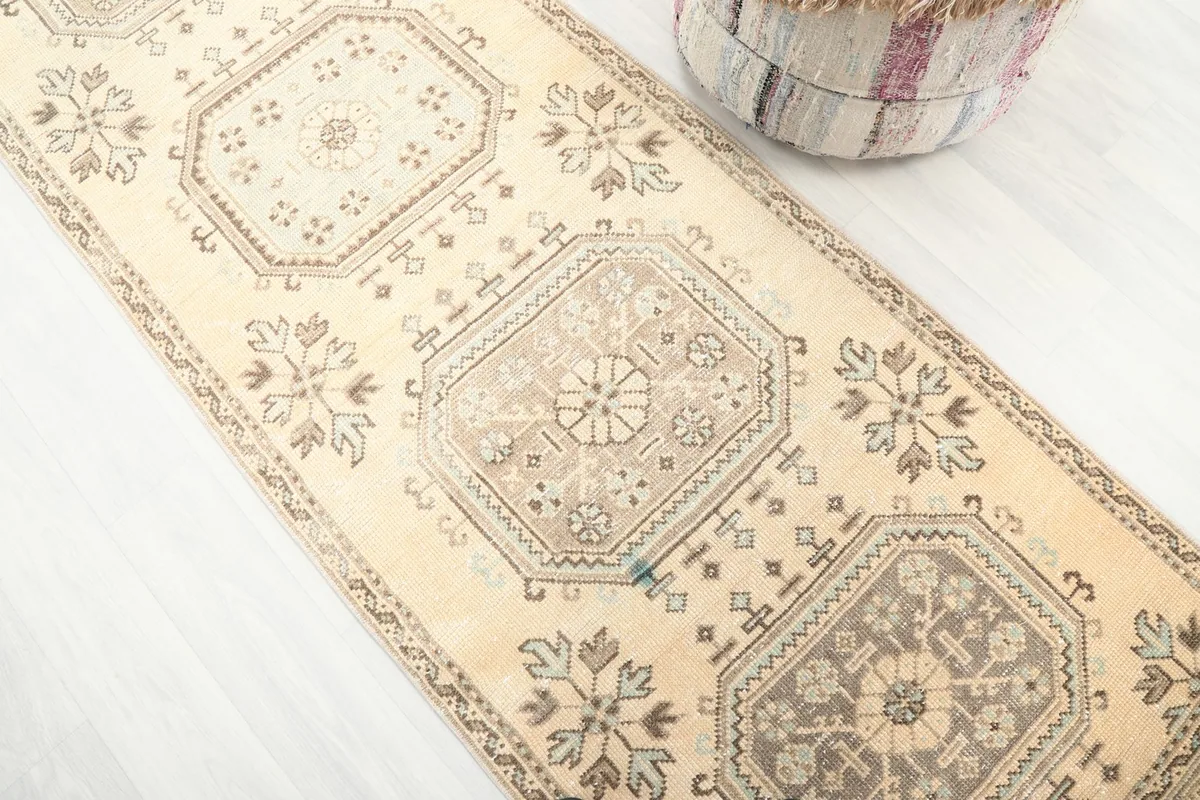 Angled view focusing on the central geometric medallions and the beige field of the runner rug