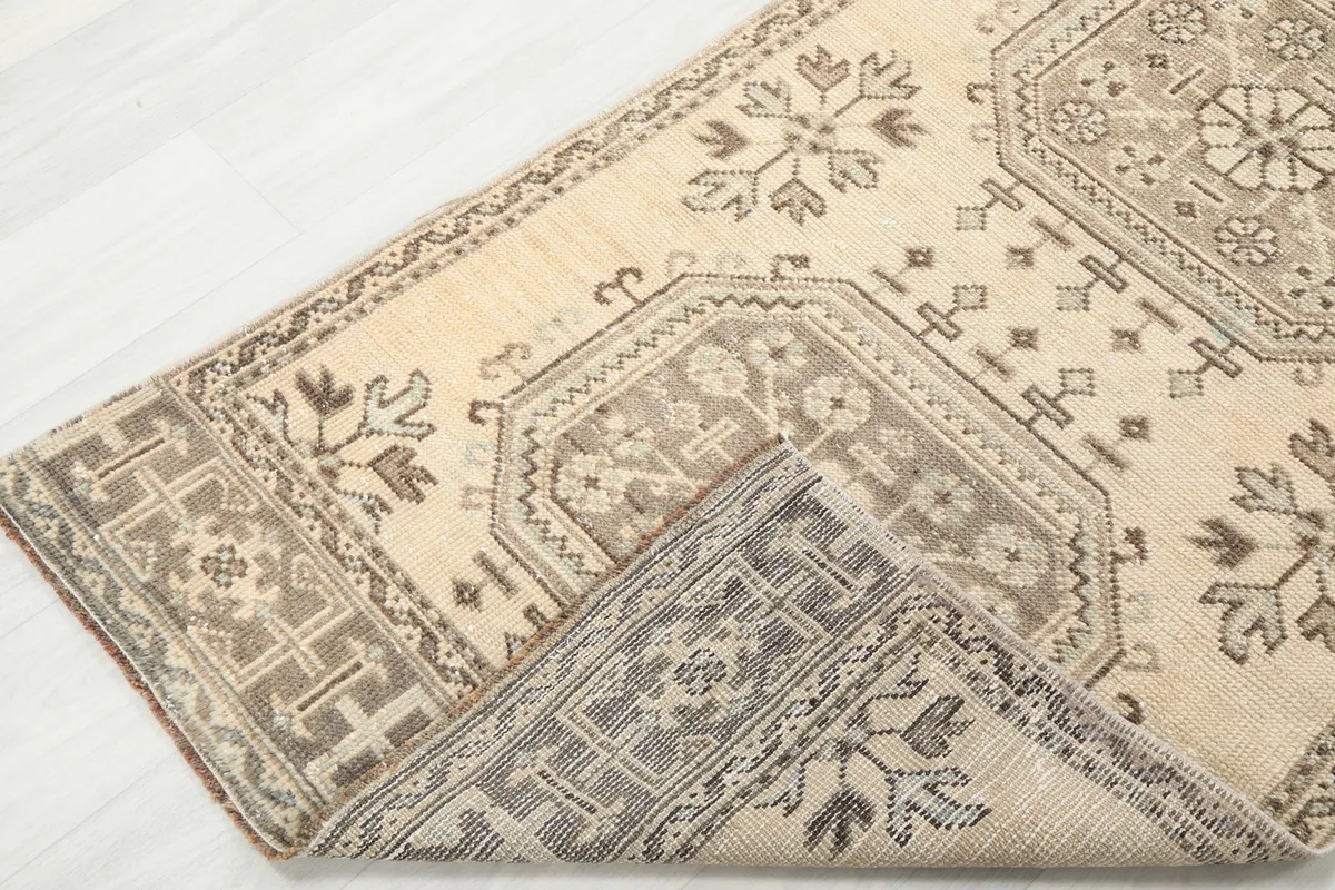 Corner of the runner rug folded back, revealing the hand-knotted wool pile and cotton foundation