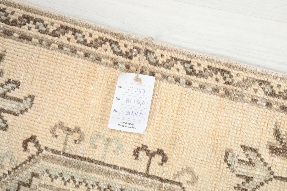 Close-up of the rug's surface with an attached product tag, showing the wool texture and vintage character