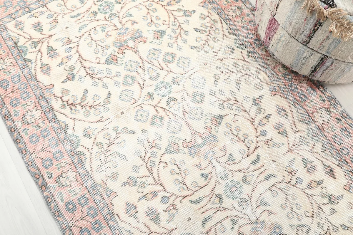 Close-up angled view highlighting the botanical patterns and soft colors of the vintage rug.