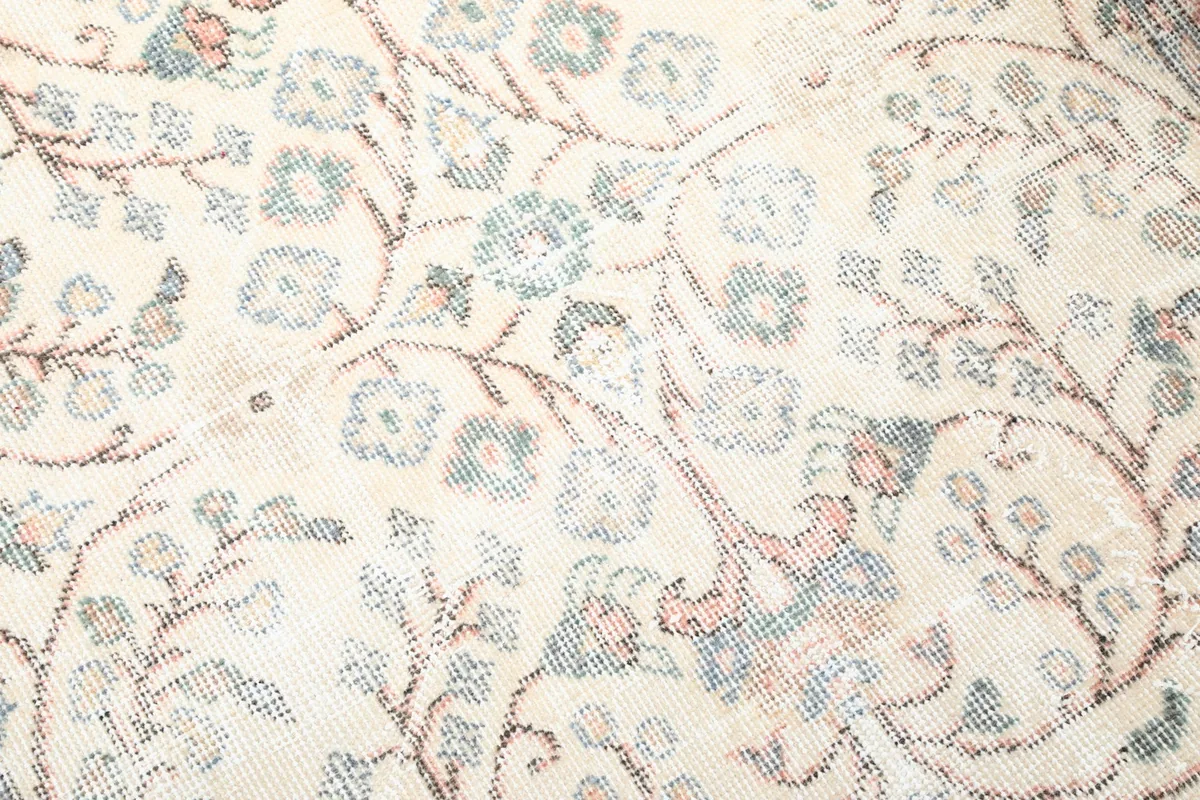 Detailed close-up of the botanical design in the ivory field of the vintage rug.