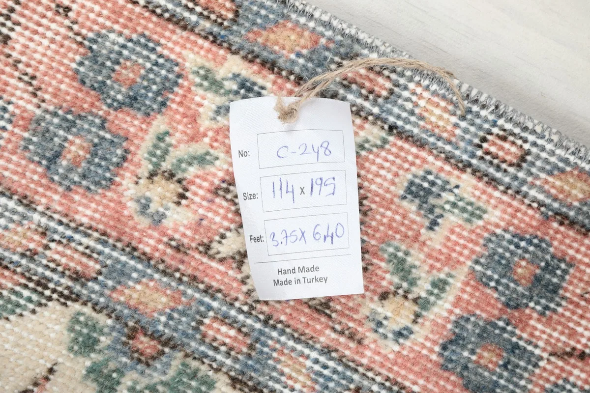 View of the rug's reverse side, showing the hand-knotted construction and care tag.