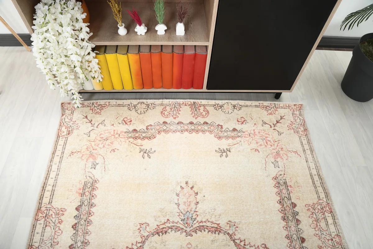 Top-down angle of the vintage rug, capturing the soft colors and floral details near a shelf