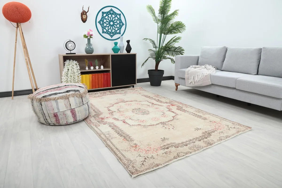 Angle view of the ivory and rose vintage rug in a living room with a gray sofa