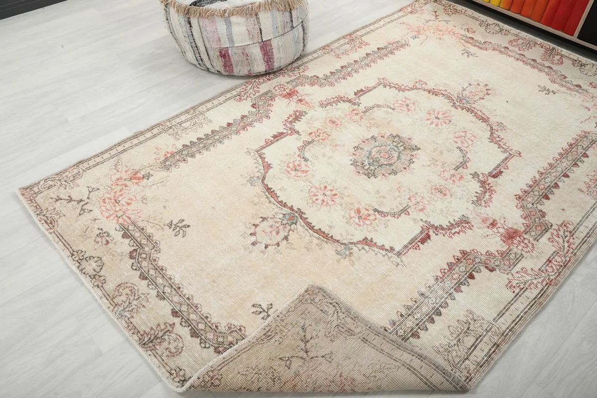 Corner of the ivory vintage rug folded back to show the reverse side and hand-knotted construction