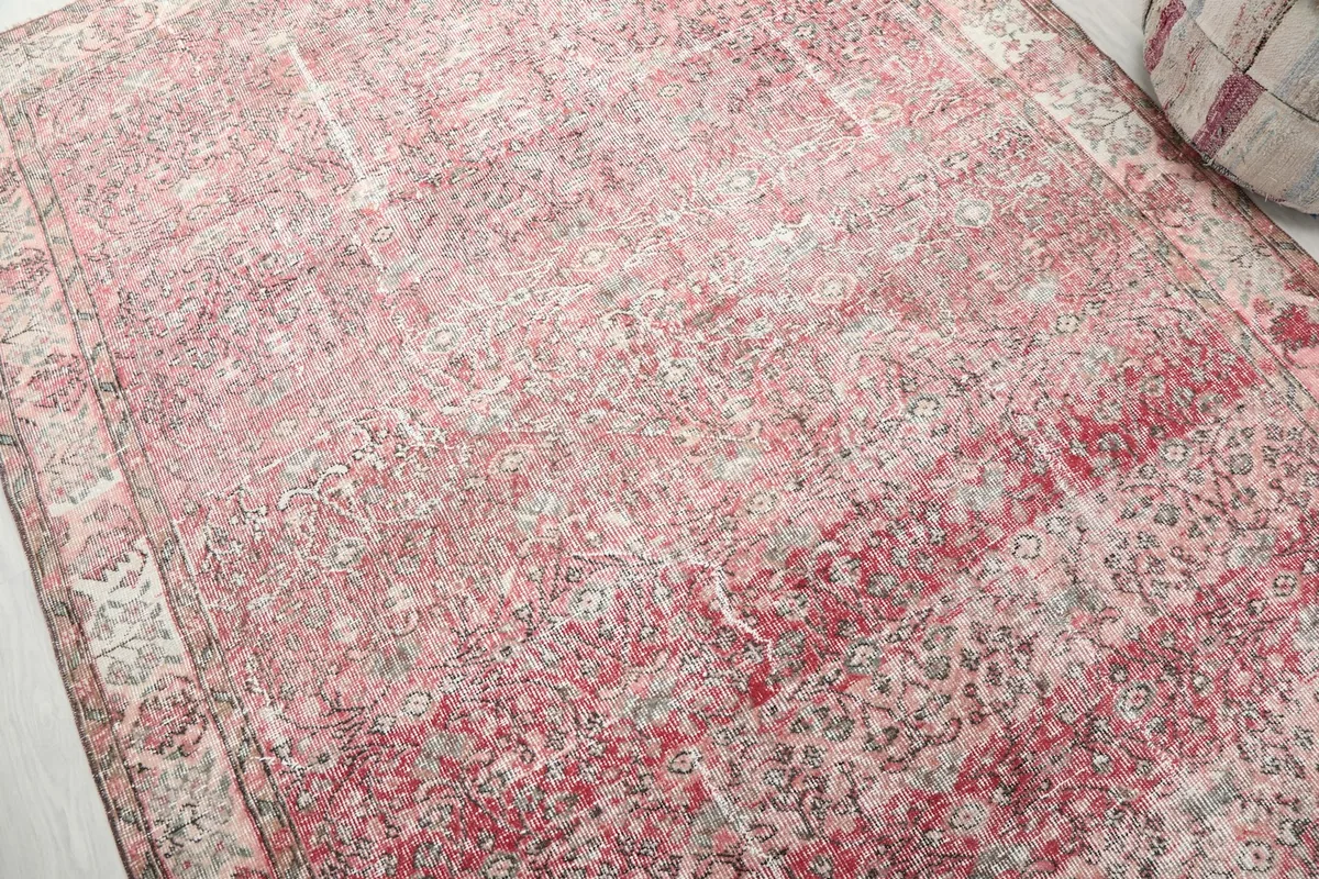 Detailed view of the distressed rose and gray floral motifs on the rug surface