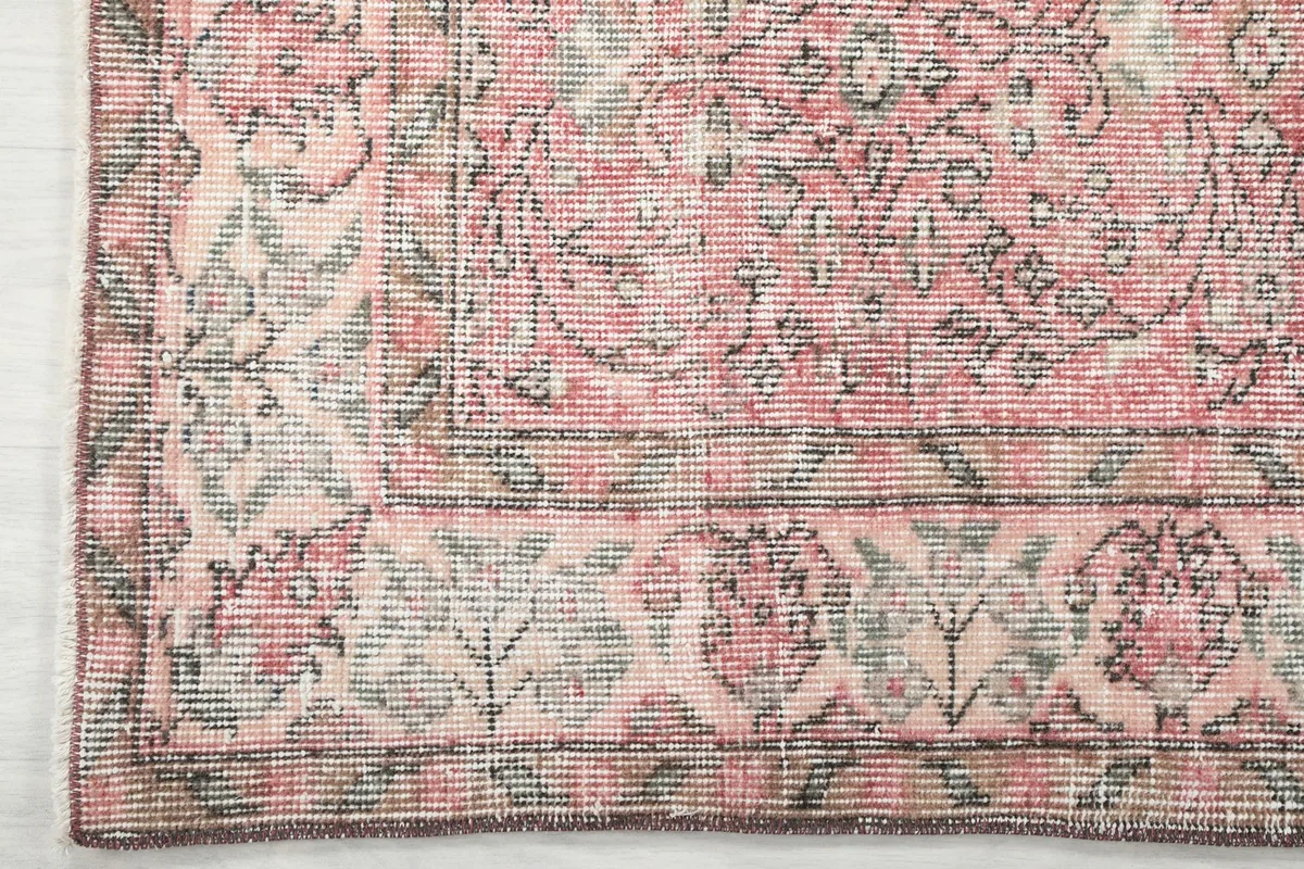 Corner detail of the rug's cream border with gray and rose floral patterns