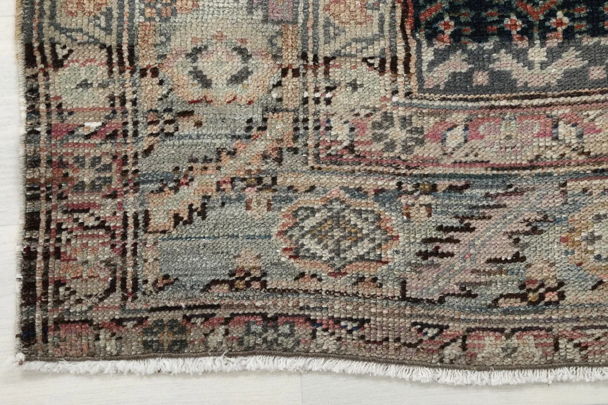 Detail of the rug's edge, revealing the worn patina and fringe