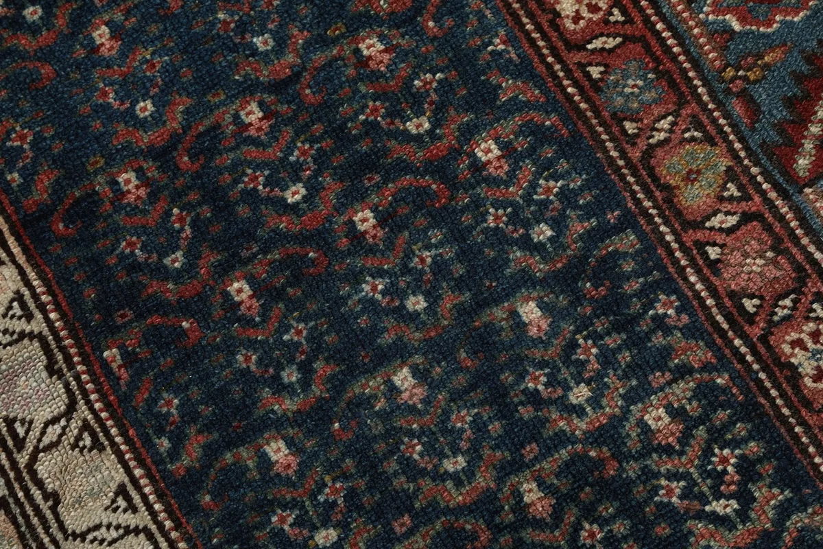Close-up of the hand-knotted wool pile, showing the intricate navy and rust patterns